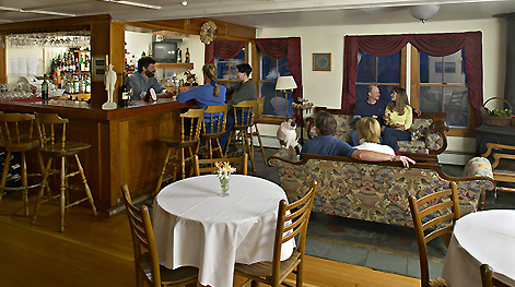 The lounge at the Vermont Inn hosts a handmade Vermont Cherry bar, wood stove and antique couches.
